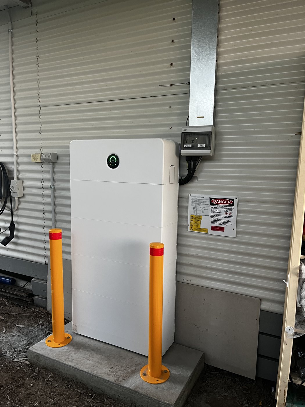 Home battery installed against a shed wall with isolation, protection and bollards, by SALTD Electrical