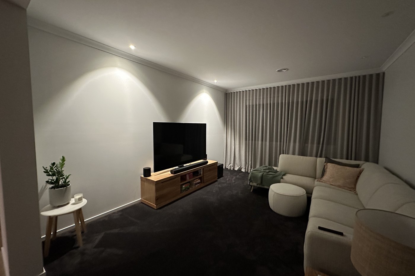 Lounge room at night with downlights washing scallops of light down the side wall behind a television, installed by SALTD Electrical